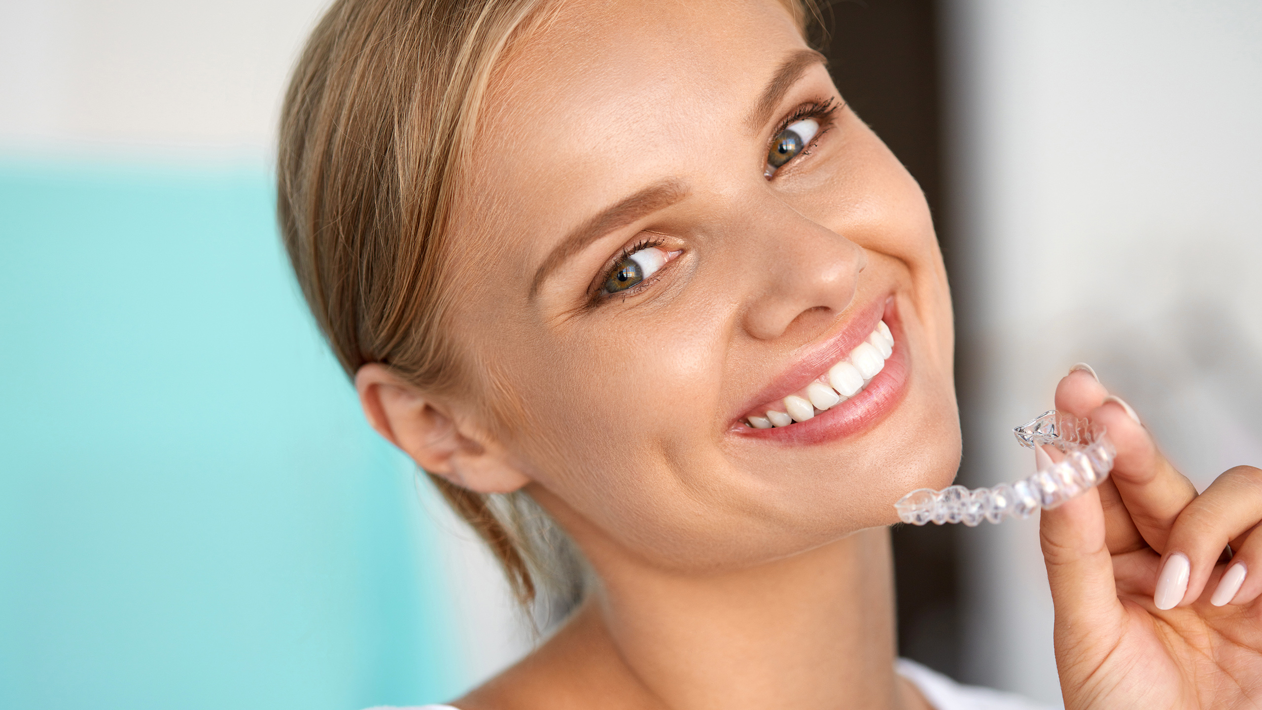 Woman smiling holding retainer